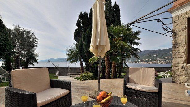 An outdoor seating area with wicker furniture and a table with fruit and drinks. - Apartments Romina (Rijeka)
