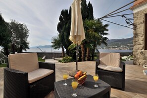 Een terras met rieten meubels en een tafel met fruit en drankjes.