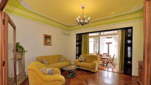 A living room with two yellow sofas, a glass coffee table, and a chandelier. - Apartments Romina (Rijeka)
