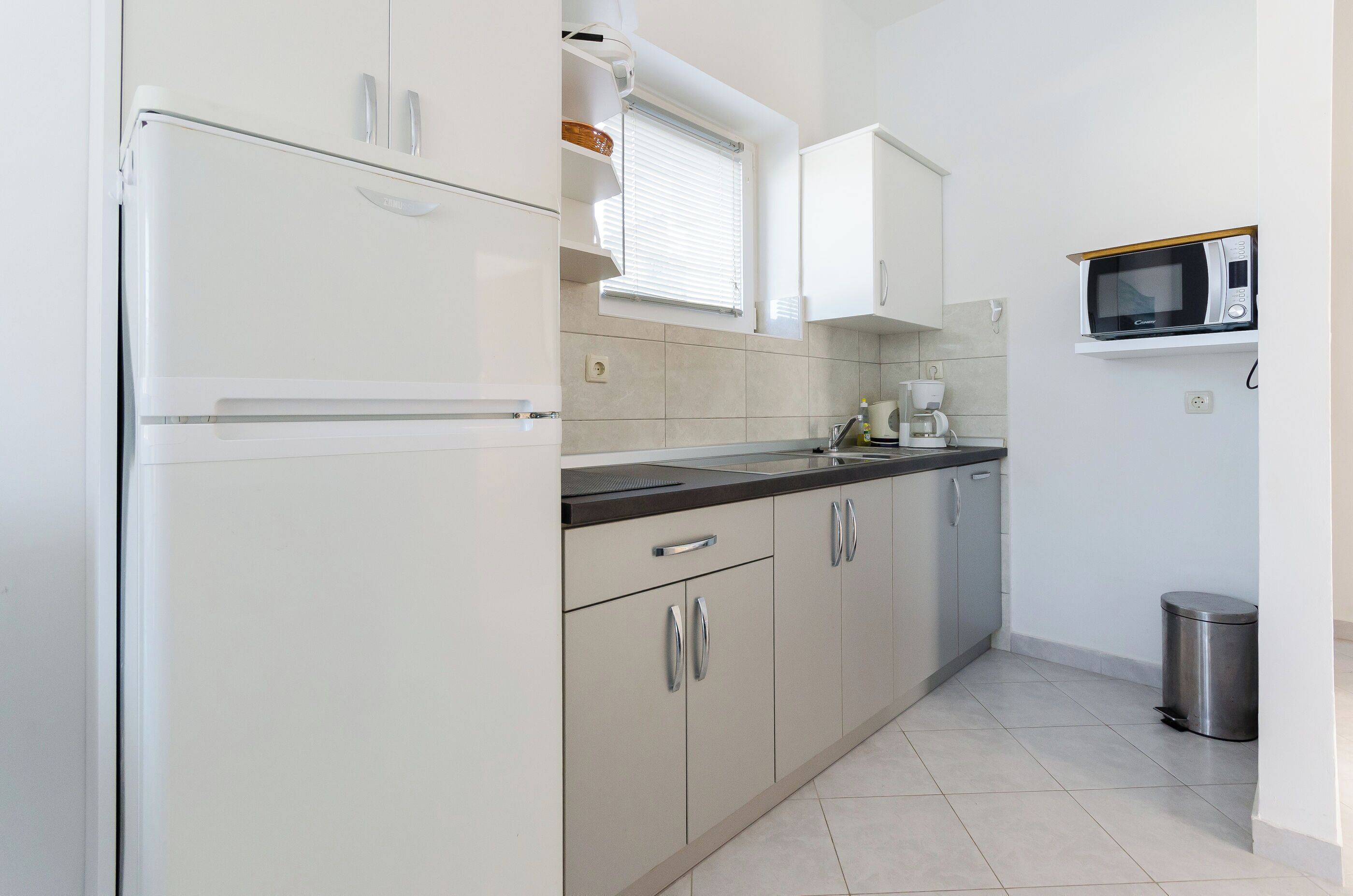 A compact kitchen with white cabinets, a built-in microwave, and a coffee maker.