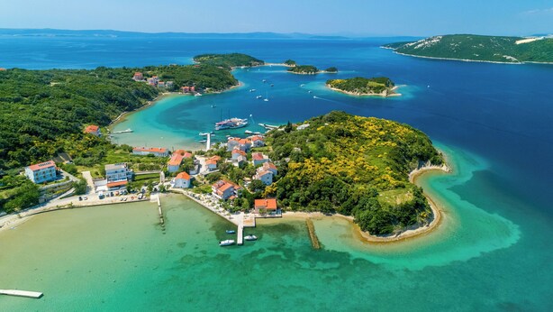 An aerial view of a coastal area with a marina, buildings, and clear blue waters. - Apartments Darko by the sea (Supetarska Draga)