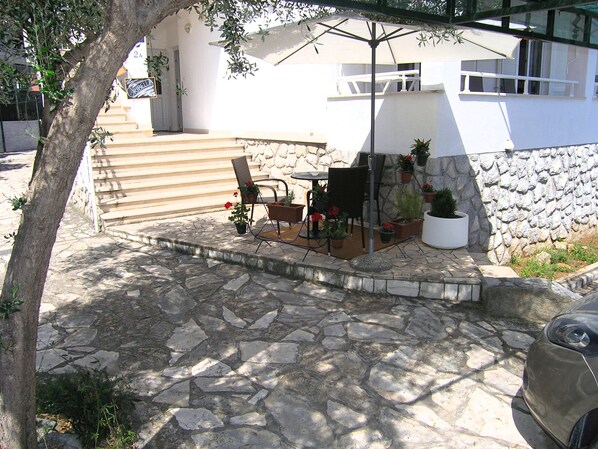 A patio with stone flooring, outdoor furniture, and potted plants. - Apartments Oribella (Krk)