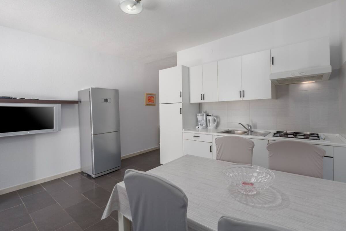 A modern kitchen with white cabinets, a built-in stove, and a large window.