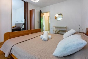 A bedroom with a bed, a mirror, a wardrobe, and a bathroom visible through an open door.