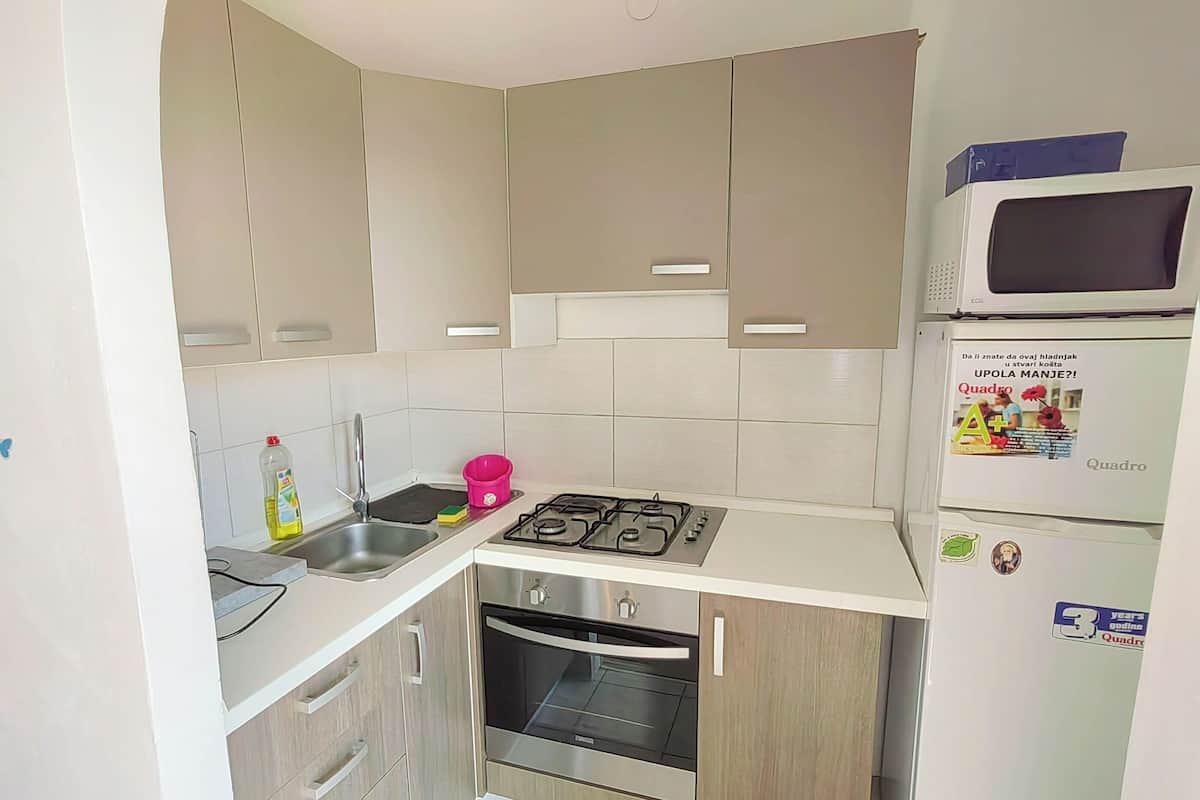 Cocina compacta con estufa a gas, horno y microondas sobre la encimera.