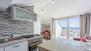 A modern kitchen with a built-in stove, a double sink, and a large window overlooking a balcony. - Apartments Anamarija (Novi Vinodolski)