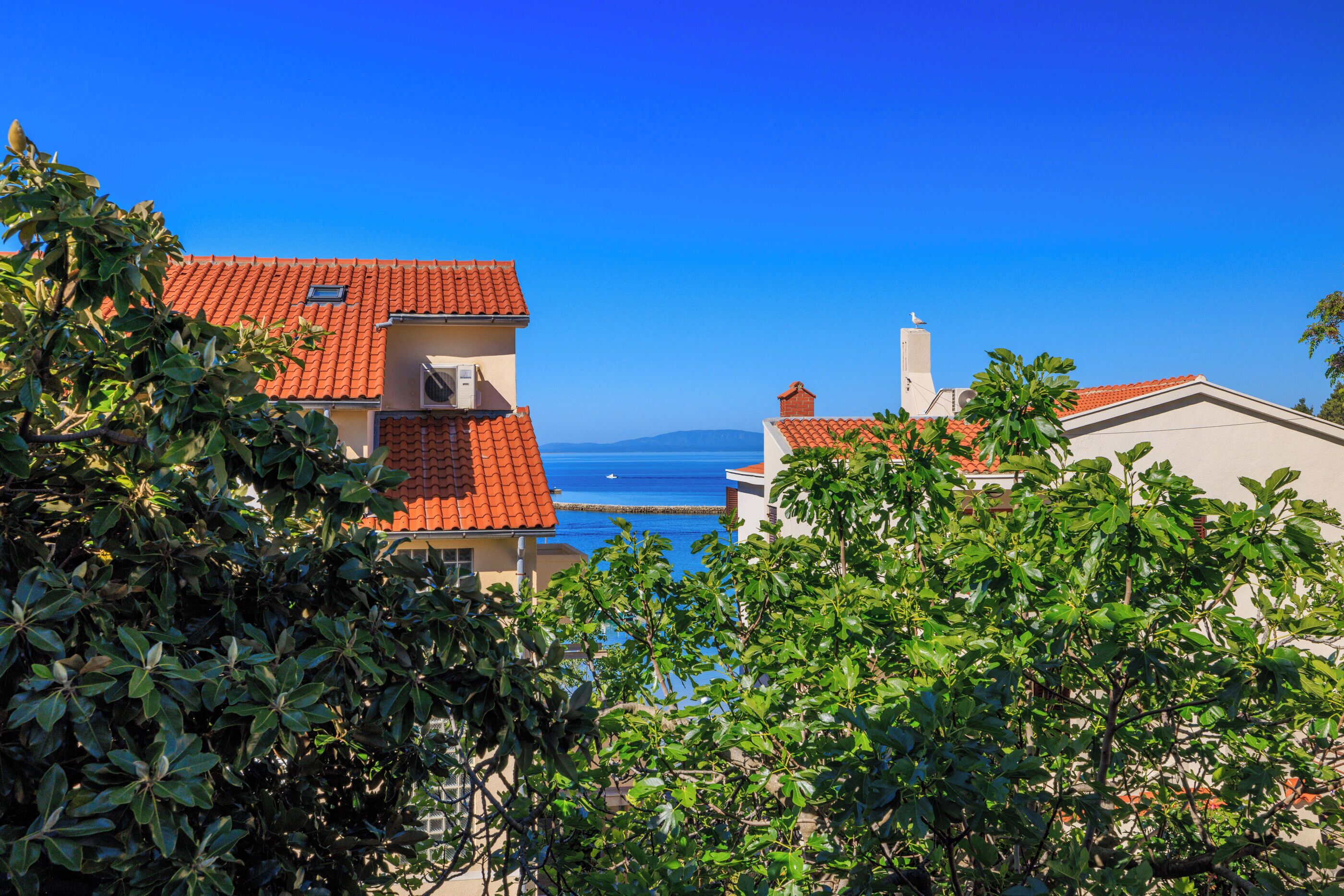 A coastal building with red-tiled roofs, surrounded by lush greenery.
