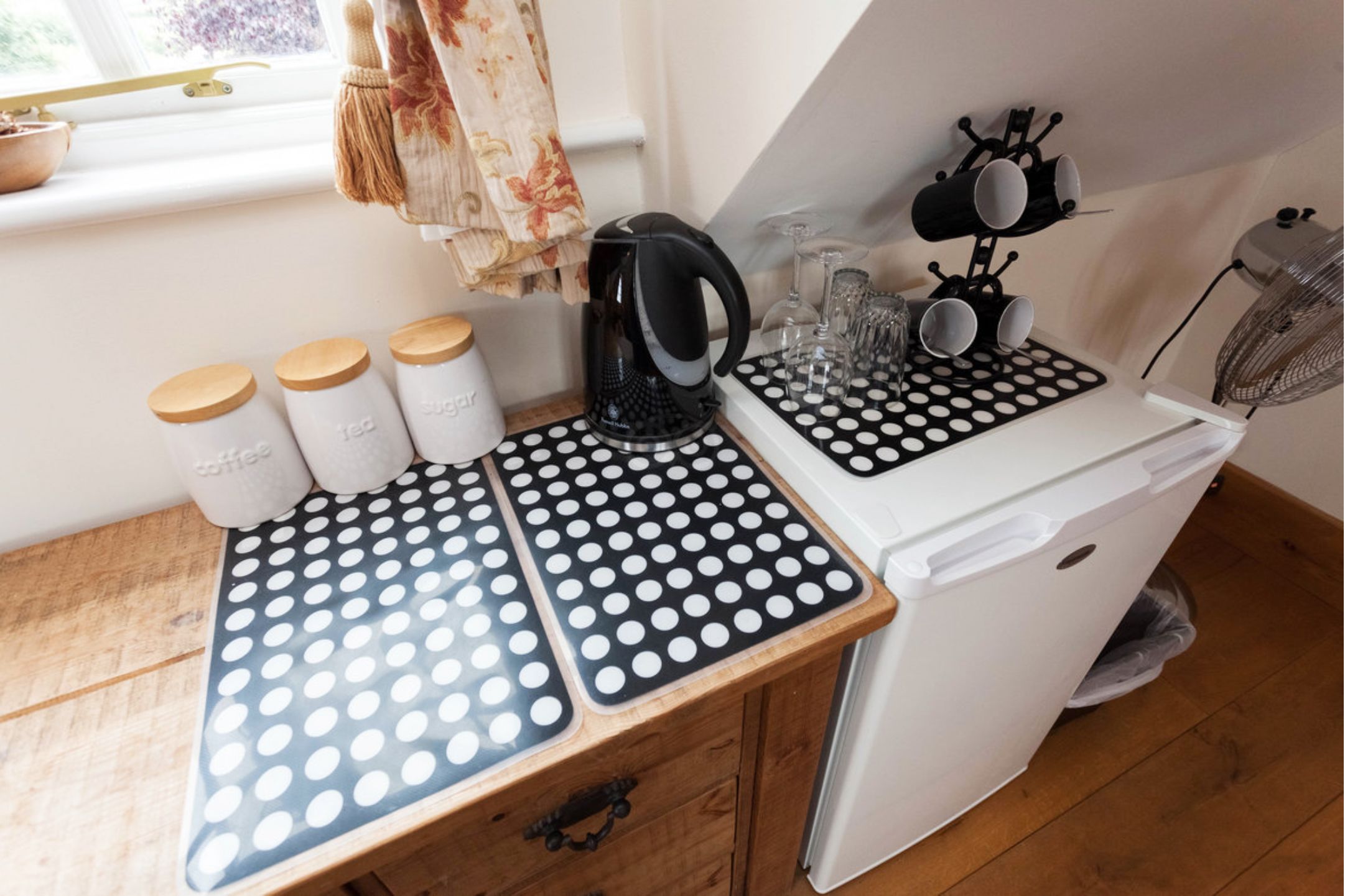 A kitchen with a countertop, kettle, and storage jars.