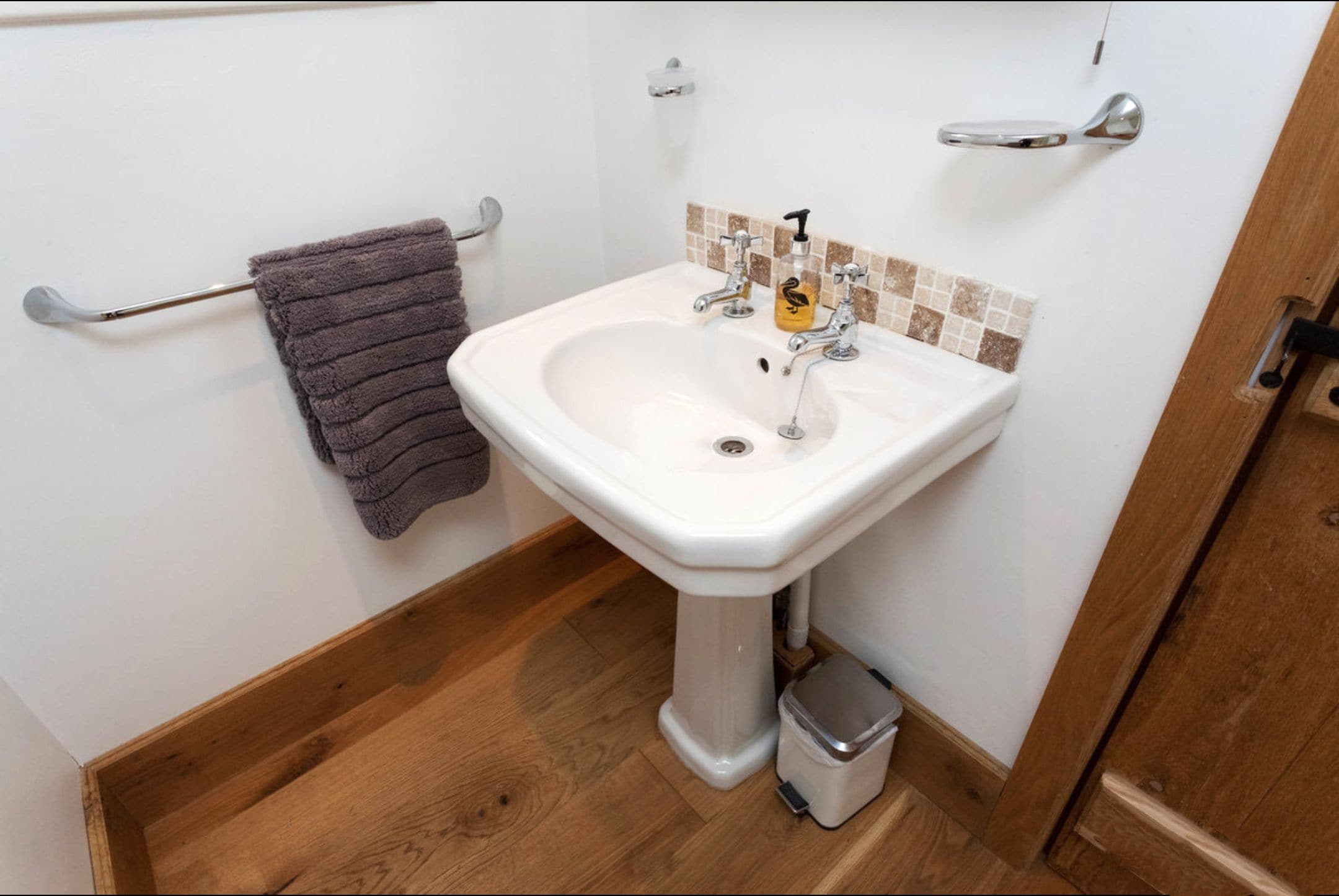 A bathroom with a white sink, a towel rack, and a trash bin.