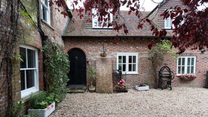 A brick house with a gravel driveway, a black door, and potted plants. - Hanger Down House Bed and Breakfast (Arundel)