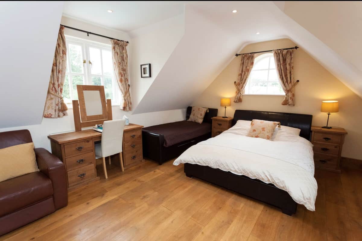 A bedroom with a large bed, a desk, a chair, and a sofa.