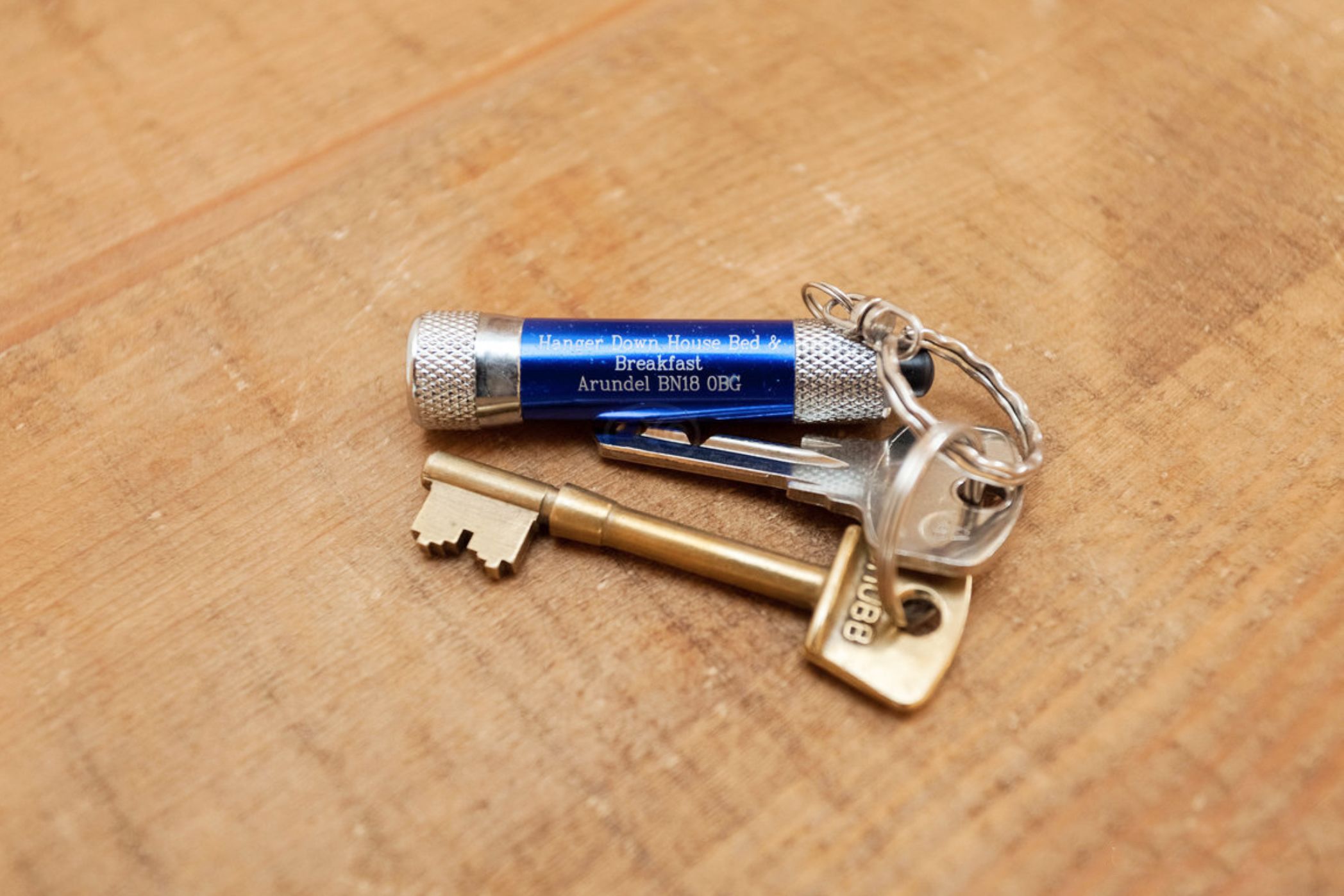 A keychain with a blue tag and a brass key on a wooden surface.