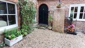 A brick house with a black door, a window, and a gravel driveway. - Hanger Down House Bed and Breakfast (Arundel)