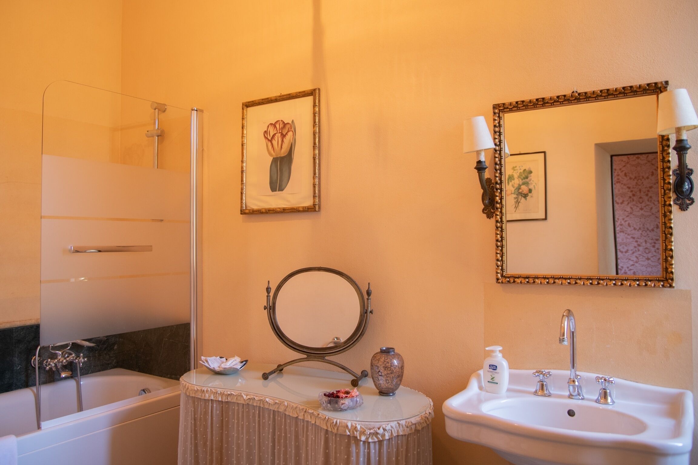 Une salle de bain comprenant une baignoire, un lavabo, un meuble-lavabo avec un miroir et un luminaire fixé au mur.