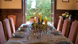 A dining table set with candles, plates, and wine glasses, with chairs around it. - Agriturismo Villa Pedone (Lucca)