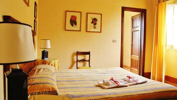 Une chambre d’hôtel avec un lit, une chaise, une lampe et deux tableaux encadrés au mur.
