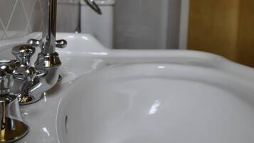 Un lavamanos con grifo cromado y un espejo encima.