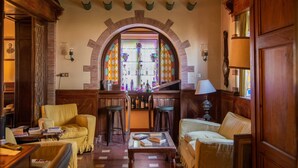 A cozy bar area with wooden furniture, a stained glass window, and a bar stocked with bottles. - Agriturismo Villa Pedone (Lucca)