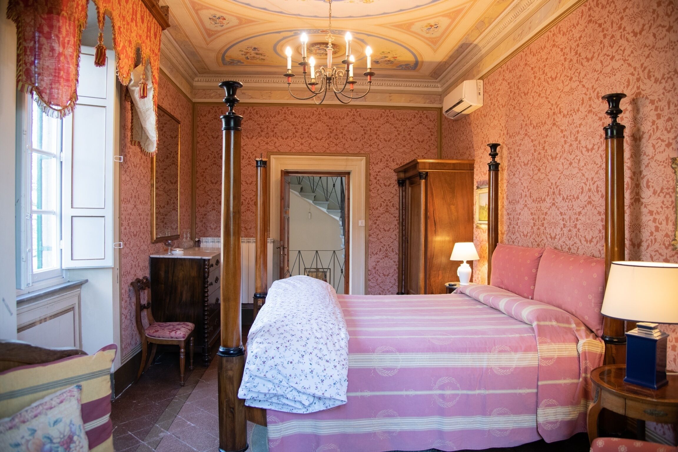 Un dormitorio con una cama con dosel, una silla, un escritorio y una lámpara.