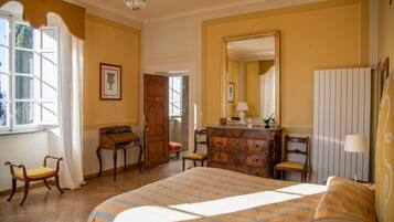 Une pièce comprenant un lit, une commode en bois, un bureau, des chaises et un grand miroir.