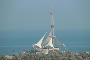 A tall tower with a lattice structure and a white canopy, surrounded by palm trees and overlooking the sea. - Dream Inn Hotel and Suites (Salmiya)