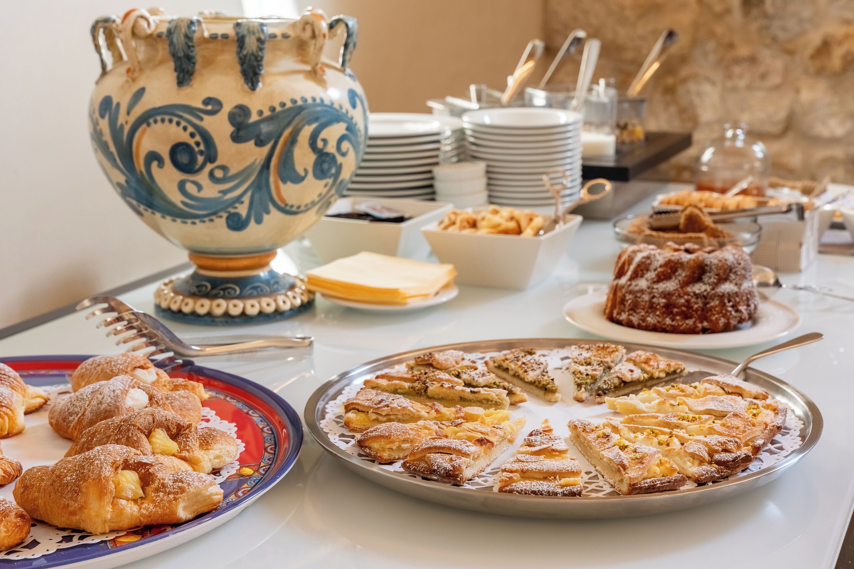 A buffet table with various pastries and a decorative ceramic jug.