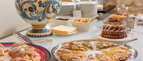 A buffet table with various pastries and a decorative ceramic jug.