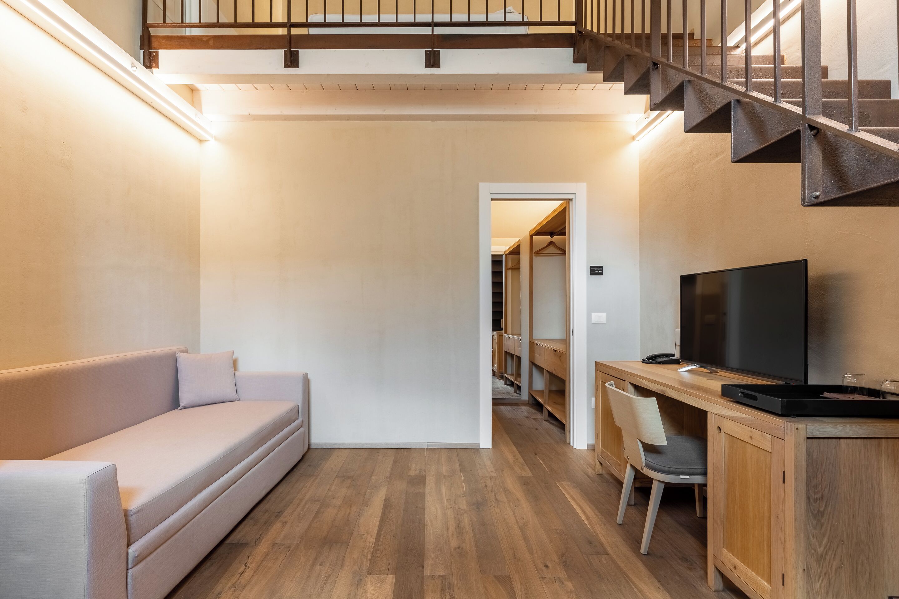Un salon moderne avec un canapé, un téléviseur et un bureau en bois.