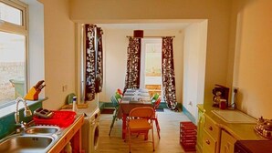 Cocina compacta con lavabo, lavadora, mesa de comedor, sillas y estufa.