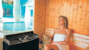 A sauna with a wooden interior, a bench, and a sauna heater.