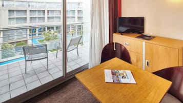 A hotel room with a balcony, a television, a small table, and a chair.