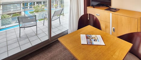A hotel room with a balcony, a television, a small table, and a chair.
