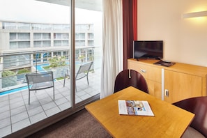 A hotel room with a balcony, a television, a small table, and a chair.