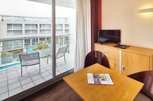 Une chambre d’hôtel avec un balcon, une télévision, une petite table et une chaise.