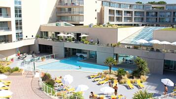 Un hôtel moderne doté d’une piscine sur le toit, de nombreux balcons et d’espaces extérieurs aménagés pour se détendre.