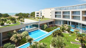 Un hôtel moderne doté d’une piscine, offrant une vue sur la mer et comprenant un jardin bien entretenu.