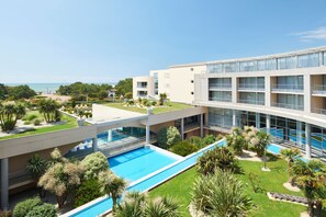 Un hotel moderno con piscina, vistas al mar y un jardín bien cuidado.