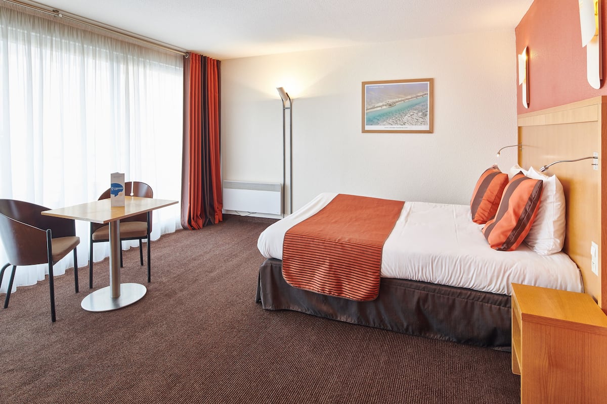 Et hotelværelse med en seng, et skrivebord og en stol.