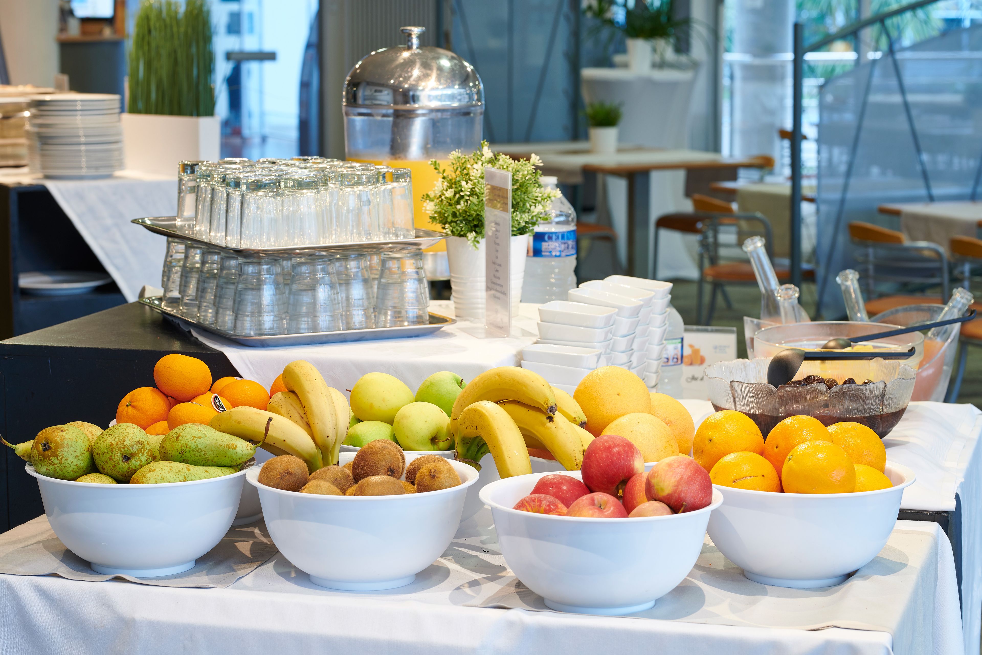 Une table de buffet avec divers fruits et un distributeur d’eau.