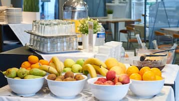 Une table de buffet avec divers fruits et un distributeur d’eau.