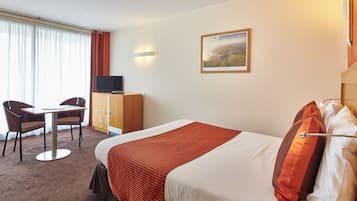 Une chambre d’hôtel avec un lit, un bureau, une chaise, une télévision et un tableau au mur.