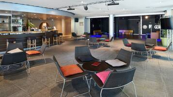 A modern lounge area with seating arrangements, a bar, and a stage for presentations.