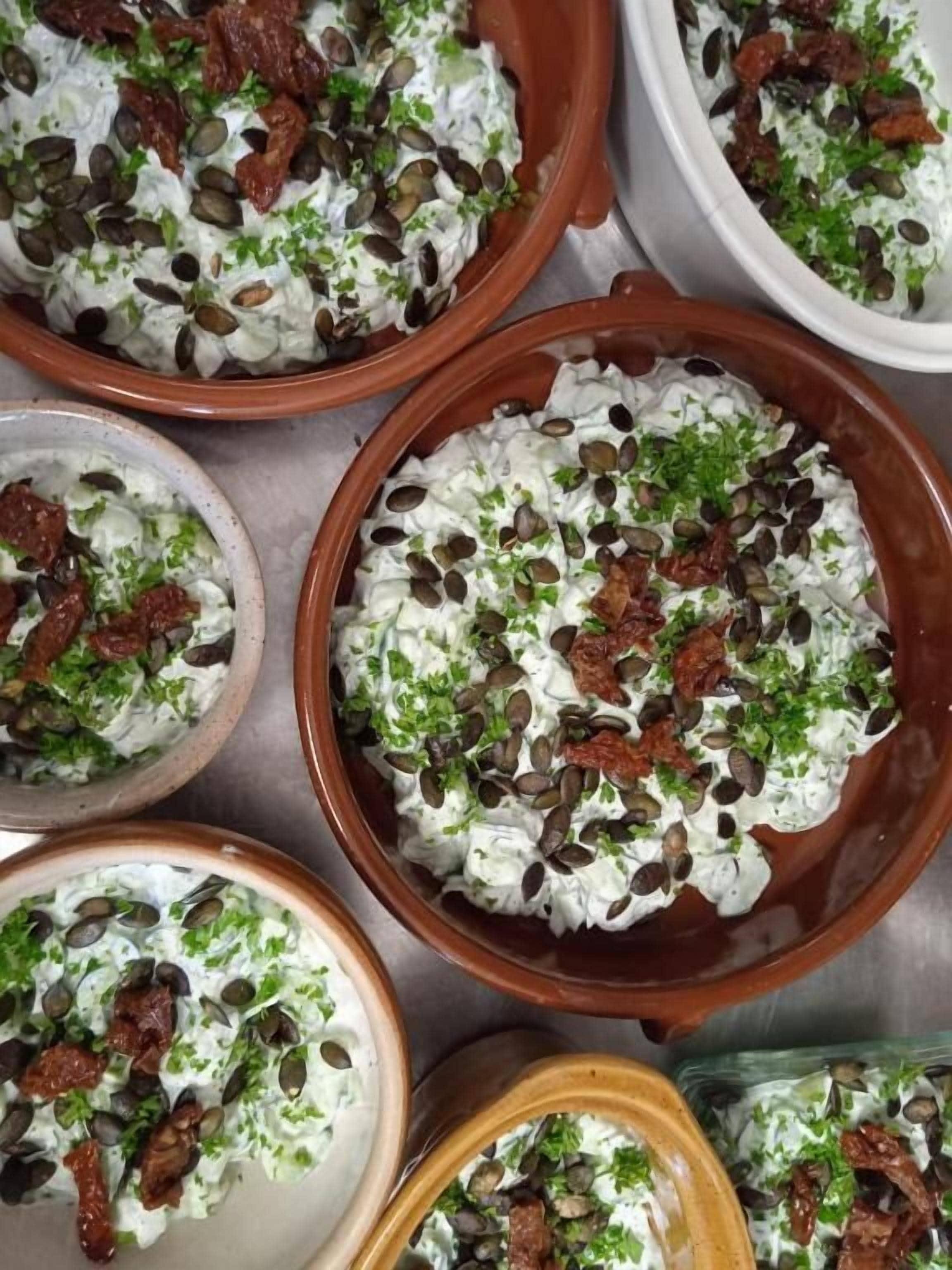 A variety of dishes in ceramic bowls with seeds and herbs.