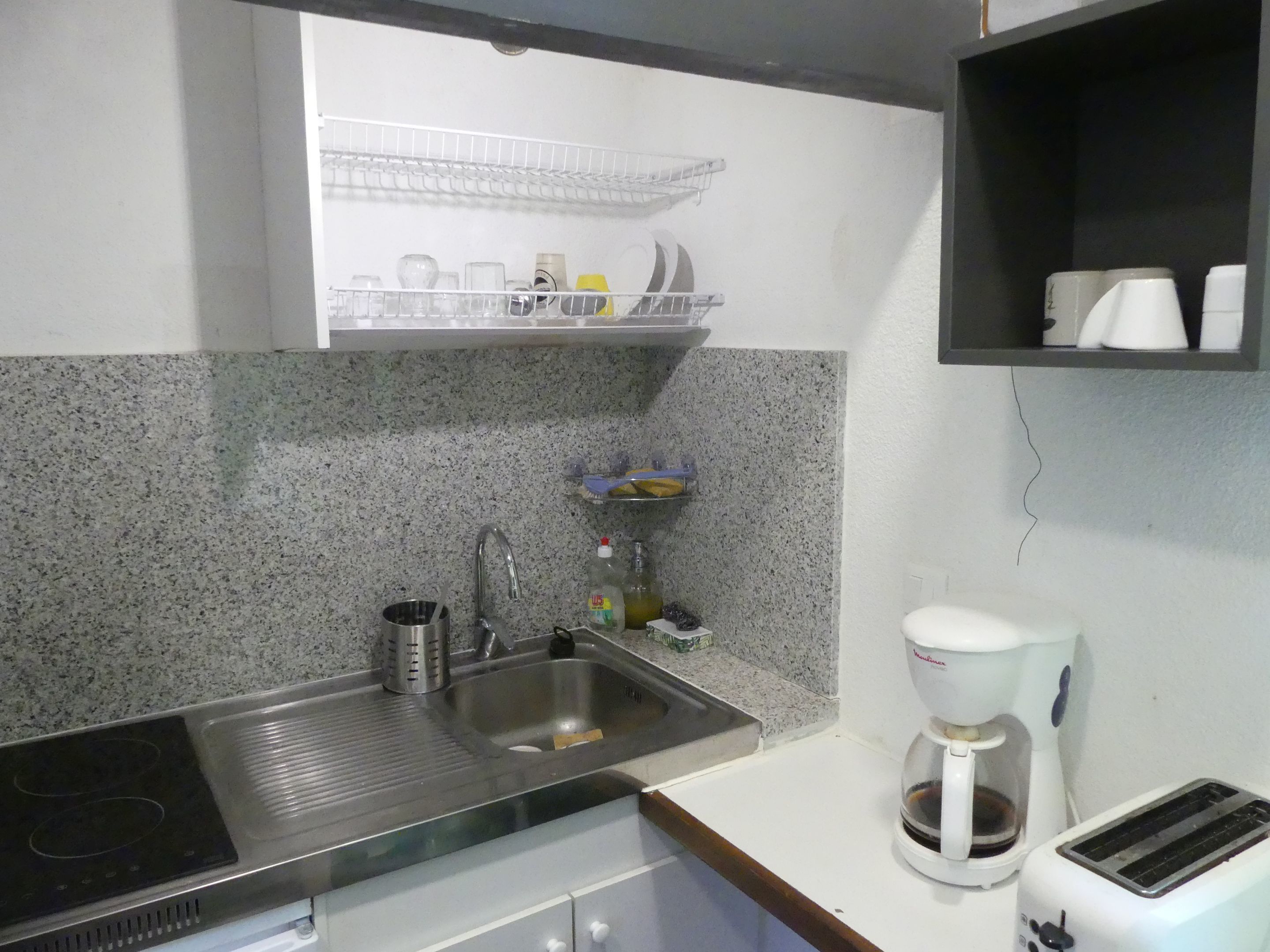 Cozinha com bancada de granito, pia de aço inoxidável, cafeteira e torradeira.