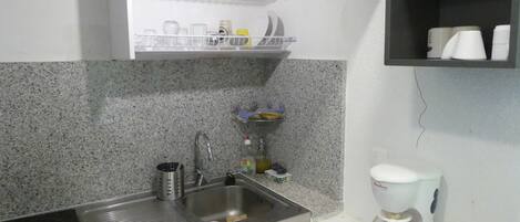 Cozinha com bancada de granito, pia de aço inoxidável, cafeteira e torradeira.