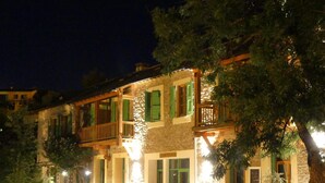 A stone building with multiple balconies, green shutters, and outdoor lighting. - Gite de Llo (Llo)