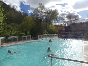 A swimming pool with people swimming and playing, surrounded by trees and a building. - Gite de Llo (Llo)