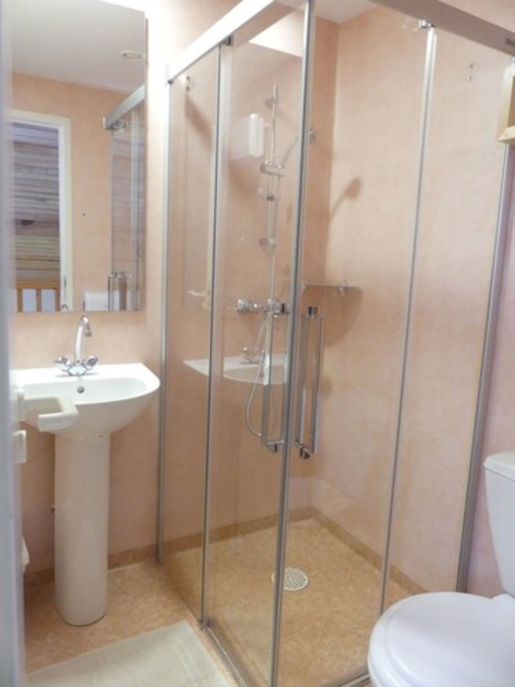 A bathroom with a glass-enclosed shower, a sink, and a toilet.