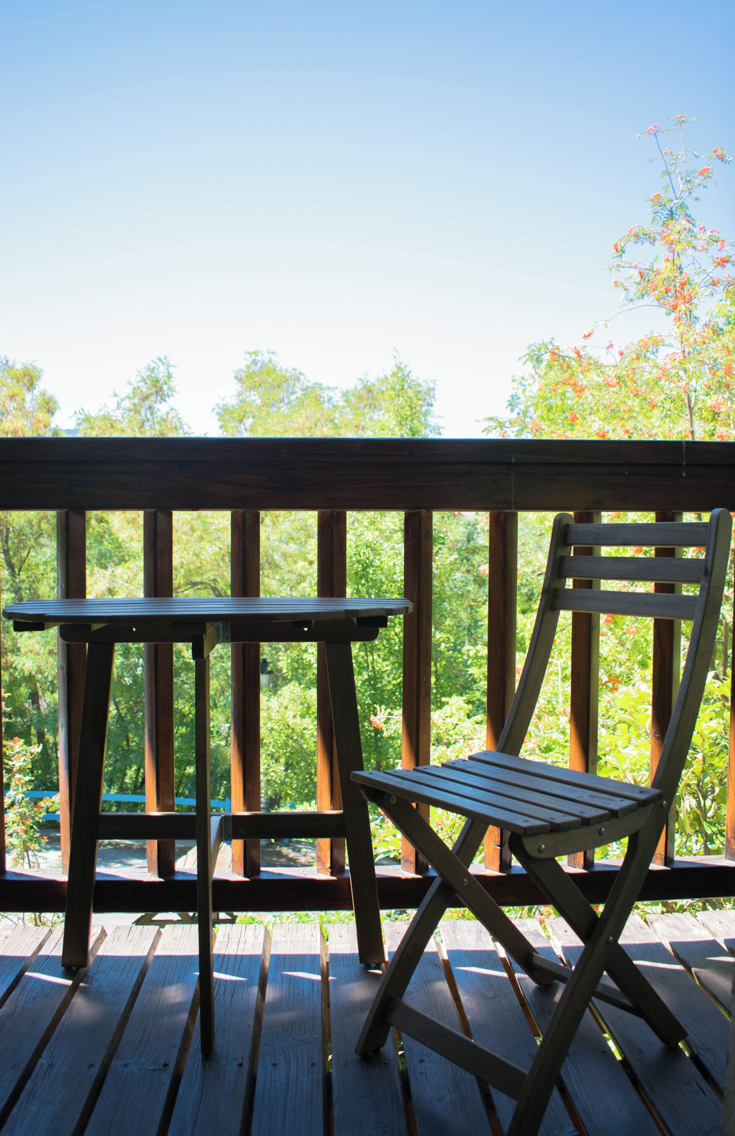 A wooden deck with a table and a chair.