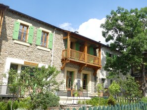 A stone building with a balcony, green shutters, and a sign indicating a restaurant. - Gite de Llo (Llo)